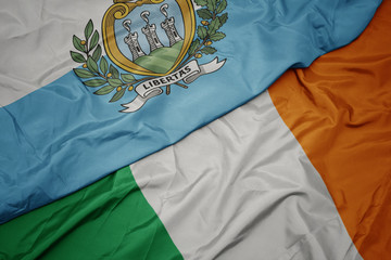 waving colorful flag of ireland and national flag of san marino.
