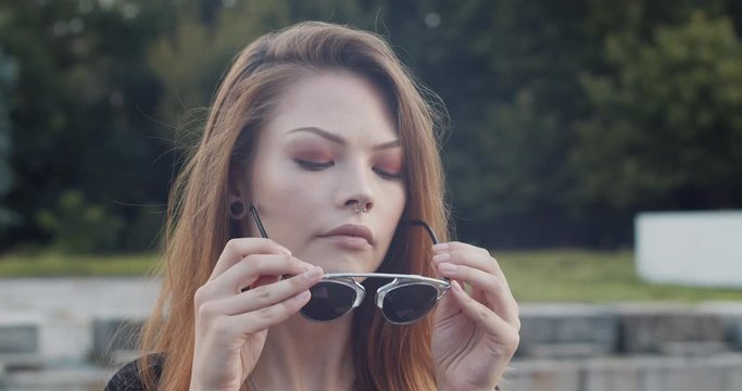 Young female model putting on fancy sunglasses slow-motion close-up 4K DCI footage