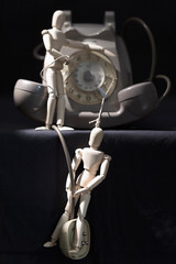 Conceptual photograph of an old telephone and mannequins: telephony makes us slaves of technology