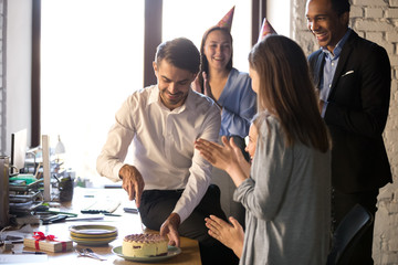 Employees celebrating birthday in office, businessman cutting cake