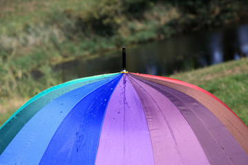 Krople deszczu na parasolce w kolorach tęczy, deszczowa pogoda.