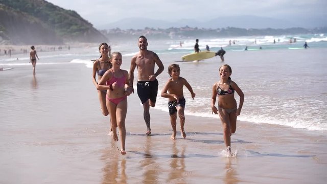 Family running on a sandy beach at low tide