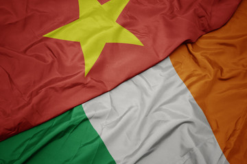 waving colorful flag of ireland and national flag of vietnam.