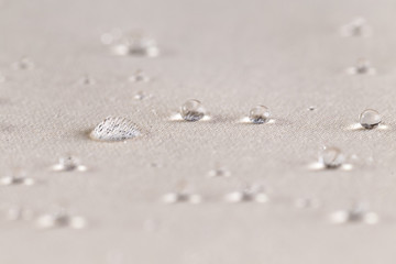 Water drops on beige waterproof fabric. Close up.