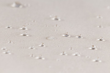 Fototapeta na wymiar Water drops on beige waterproof fabric. Horizontal image.