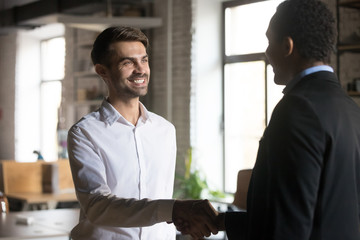 Smiling employee handshaking with executive, getting job or reward