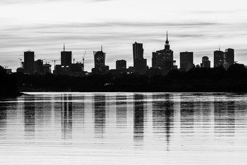 Black and white urbanscape with skyscrapers and the reflection in the river. Warsaw, capital of Poland on the Vistula River.