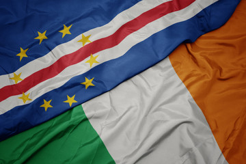 waving colorful flag of ireland and national flag of cape verde.
