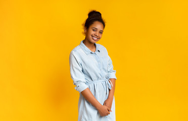 Obraz na płótnie Canvas Timid african girl posing over yellow studio background