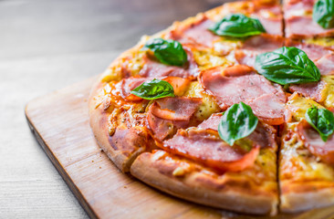 Pizza with Mozzarella cheese, ham, tomato sauce, pepper, Spices and Fresh basil. Italian pizza on wooden table background