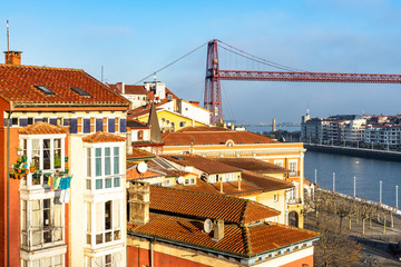 Iron tower of the Vizcaya Bridge emerging between the colorful buildings and roofs of Portugalete, Basque Country, Spain