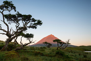 First yellow red sunlight falling onto Ponta da Pico, Portugals highest mountain on Pico Island as seen from Lagoa do Capitão.