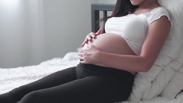 Close-up portrait Young woman pregnant a beautiful sitting on the white bed