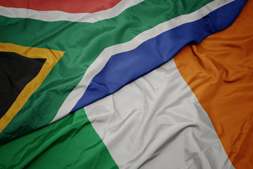 waving colorful flag of ireland and national flag of south africa.