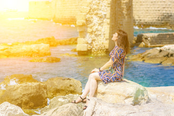 Side view of a woman watching sun on the beach at sunset. Mature woman relaxing on sea beach, hot sunny day.