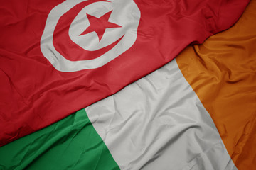 waving colorful flag of ireland and national flag of tunisia.