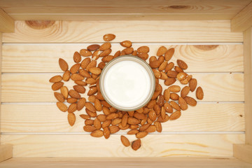 Healthy diet drink almond milk. A glass of white almond milk with almond nuts around in a wooden box. Healthy living concept. Flat lay or top view.