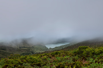 Landscape of low clouds and bad weather over Lagoa Funda das Lajes caldera volcanic crater lake at Ilha das Flores island in the Azores