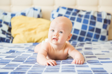Adorable baby boy in white sunny bedroom. Newborn child relaxing in bed. Nursery for young children. Textile and bedding for kids. Family morning at home