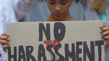Upset girl holding banner with No harassment slogan, against domestic violence