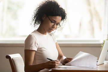 Focused biracial woman in glasses study correct paperwork - Powered by Adobe