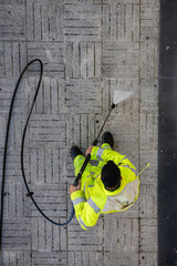 Worker cleaning the street sidewalk with high pressure water jet