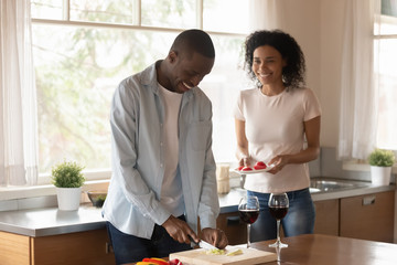 Happy african American couple cook food at home together