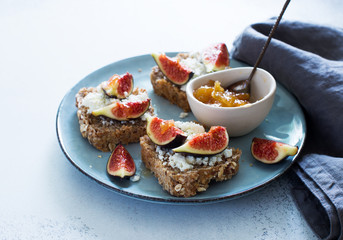 Open sandwiches with soft cheese and figs on a blue plate