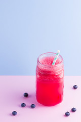 Watermelon smothie in mason jar with slices of watermelon. Watermelon smoothies and blueberries on pink blue background. Healthy drink for vegan. Copy space