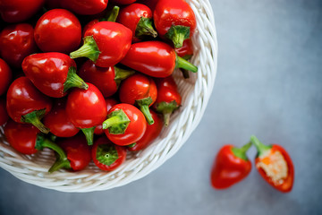 Red chili peppers in a white basket on a gray background.