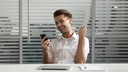 Cheerful successful motivated euphoric young manager celebrating financial success.