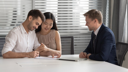 Happy mixed race married spouse signing contract with bank manager.