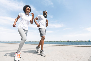 Black Man And Woman Running Along River Embankment In City