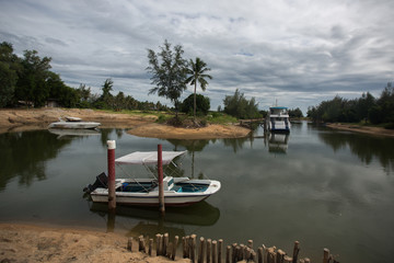a small lake with boats surrounded with trees on a cloudy day near Koh Talu Island, Thailand