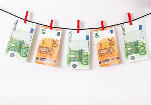 Euro banknotes hanging on a clothesline against white background. Euro money with red clothes pegs on rope. Money Laundering euro hung out to dry. Isolated euro money on string.