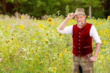 handsome bavarian man in his 50s standing in a field of sunflowers