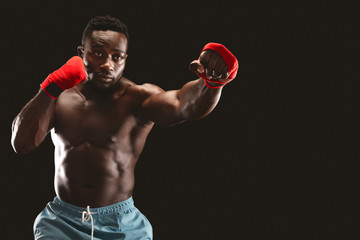 Focused african boxer fighting over black background