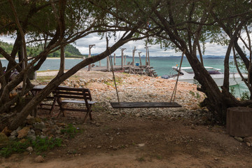 a peaceful resting area with a wooden bench and a traditional swing, near the beach at Koh Talu, Thailand