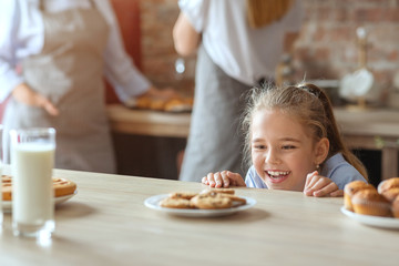 Charming little girl on kitchen looking with joy at sweets