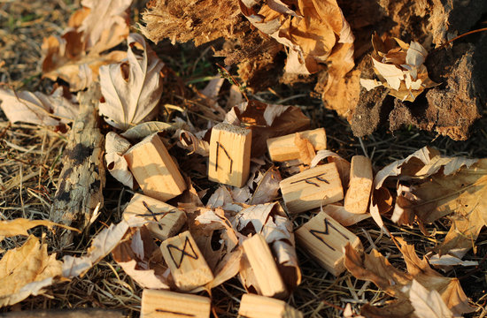 Horizontal view  on the Wooden Runic alphabet with the central rune Uruz which lies on the yellow foliage. Set for a magic ritual. Bluer effect
