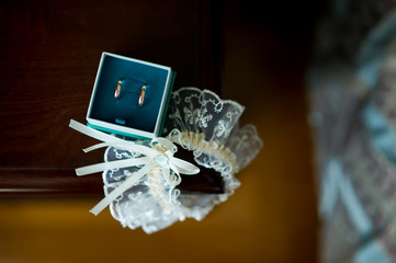a box with rings and a garter lie on the edge of the bedside table near the bed