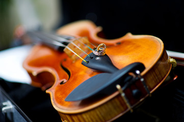 Fototapeta premium wedding rings lie on the edge of the violin with strong bokeh