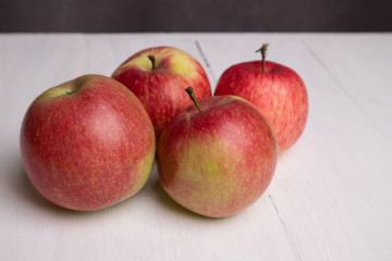 four red apples on a white board