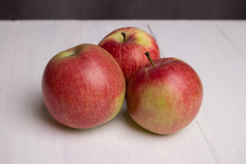 three red apples on a white board