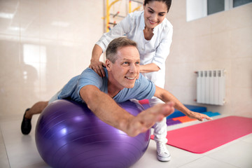 Smiling doctor helping to do rehab exercises