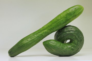 Two cucumbers, one twisted and the other one straight, showing the concept ”Same but different”.