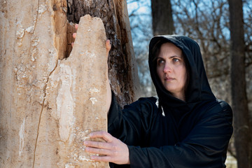 Hooded Woman in black robes deep in the Forest. Witches. Halloween and Gothic concept. Witchcraft and magic. Scary. 