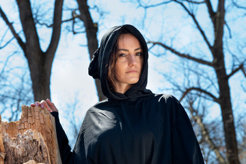 Hooded Woman in black robes deep in the Forest. Witches. Halloween and Gothic concept. Witchcraft and magic. Scary. 