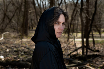 Hooded Woman in black robes deep in the Forest. Witches. Halloween and Gothic concept. Witchcraft and magic. Scary. 