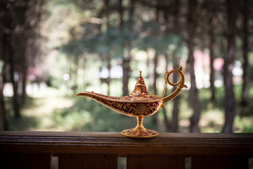 Antique artisanal Aladdin Arabian nights genie style oil lamp at the forest. Lamp of wishes fantasy...